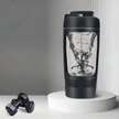 Black protein shaker with measurement markings on a white surface with dumbbells.