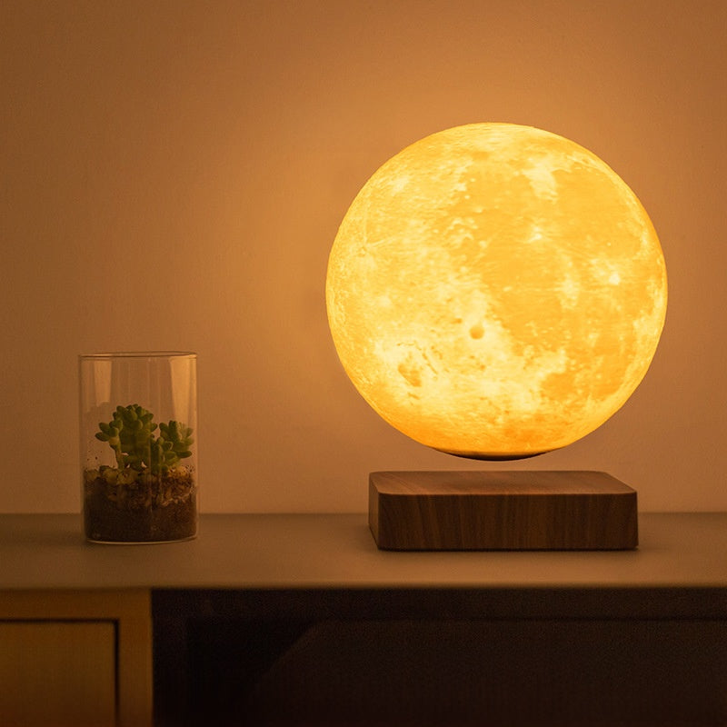 Levitating moon lamp on a wooden base with a small plant in the background