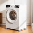 White washing machine on a wooden floor with a light-colored wall in the background