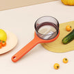 Orange kitchen strainer on a light surface with vegetables around