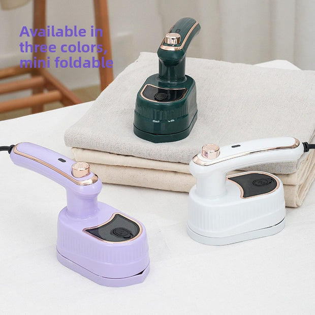 Three mini foldable steamers in different colors on a table with folded cloths.