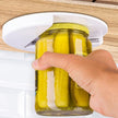 Hand using a jar opener on a jar of pickles