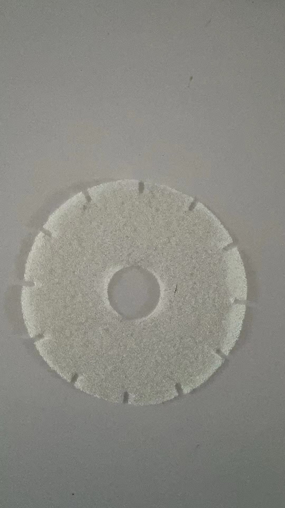 Round white filter disc on a gray background