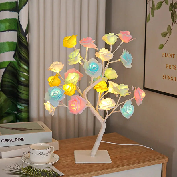 Colorful LED tree lamp on a wooden table with books and a cup in the background.