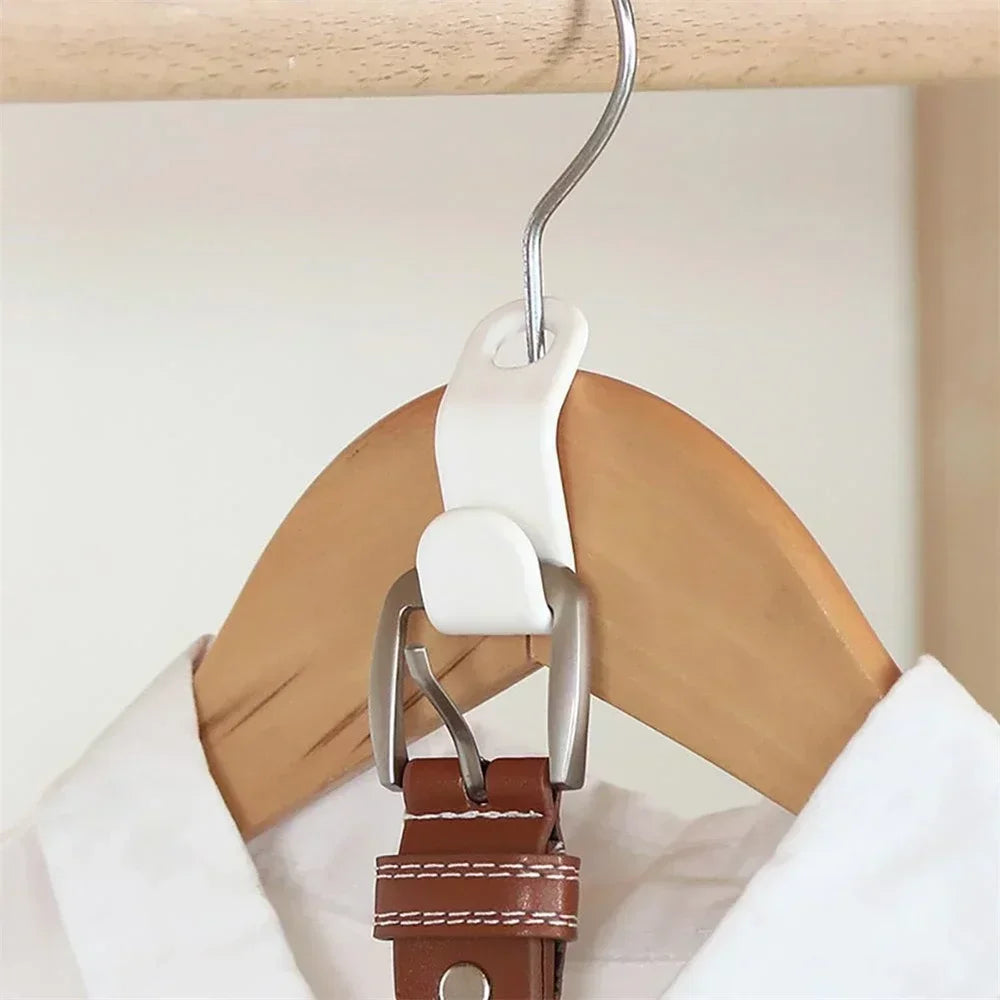 White clip attached to a brown leather belt on a wooden hanger against a white background