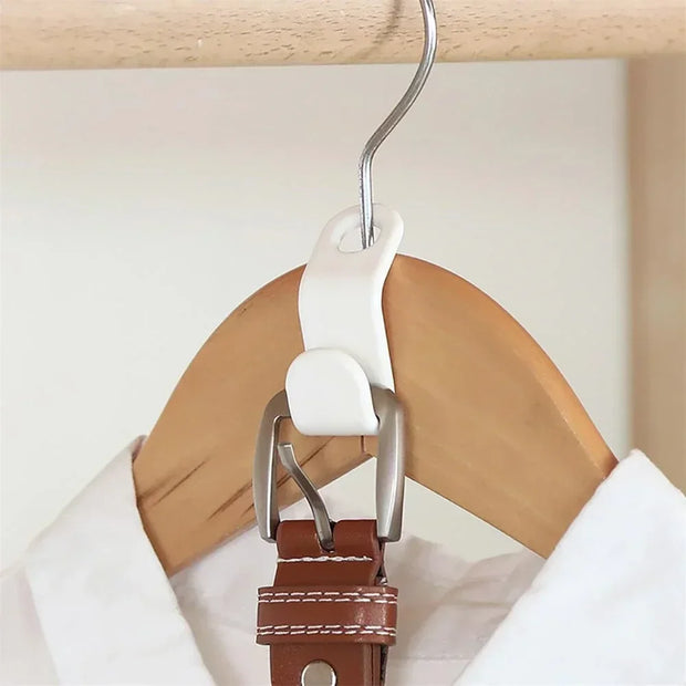 White clip attached to a brown leather belt on a wooden hanger against a white background