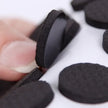 Close-up of a hand holding a black circular object with more black circular objects on a white background.