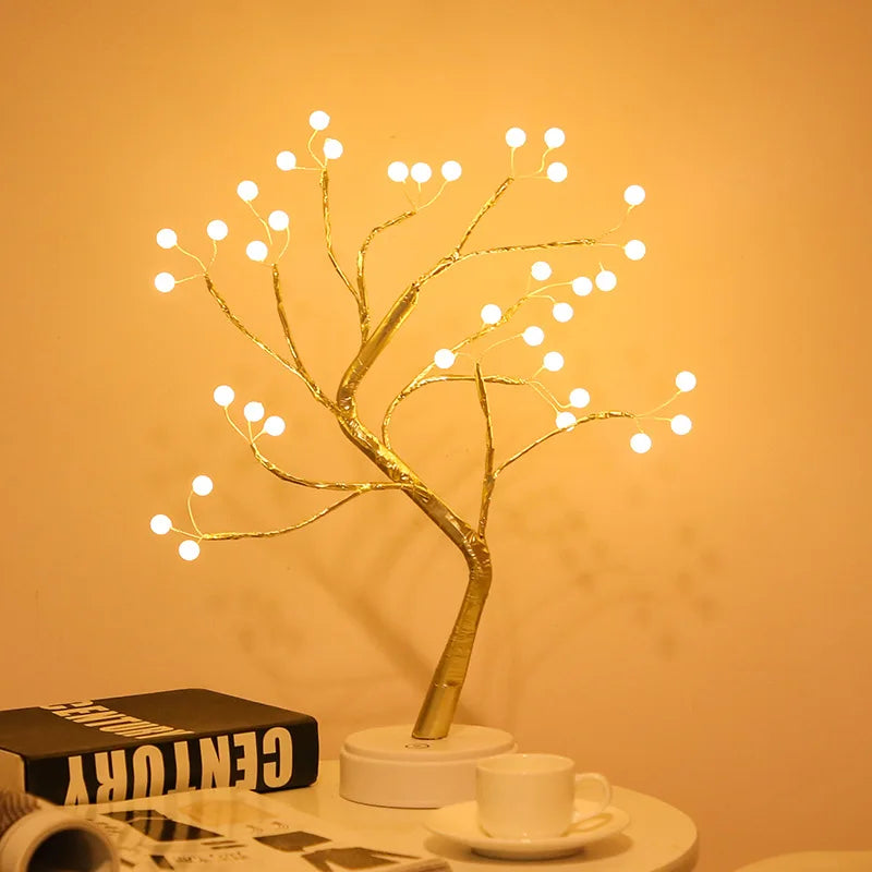 Decorative LED tree with lights on a table against an orange wall
