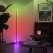 Room interior with a standing lamp casting colorful light, a framed poster on the wall, and a small table with decorative items.