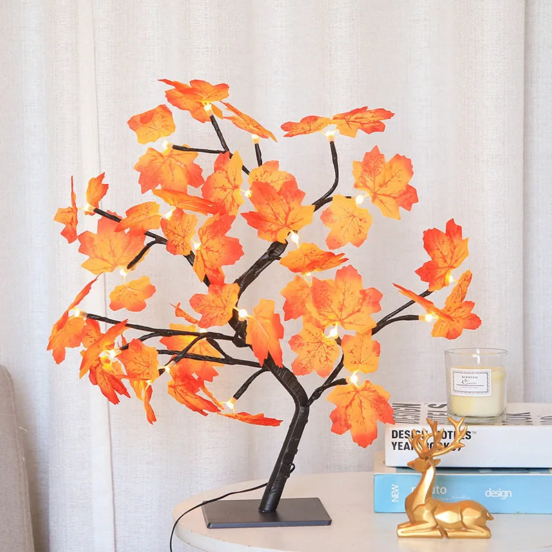 Decorative lamp with orange leaves on a table next to books and a candle.