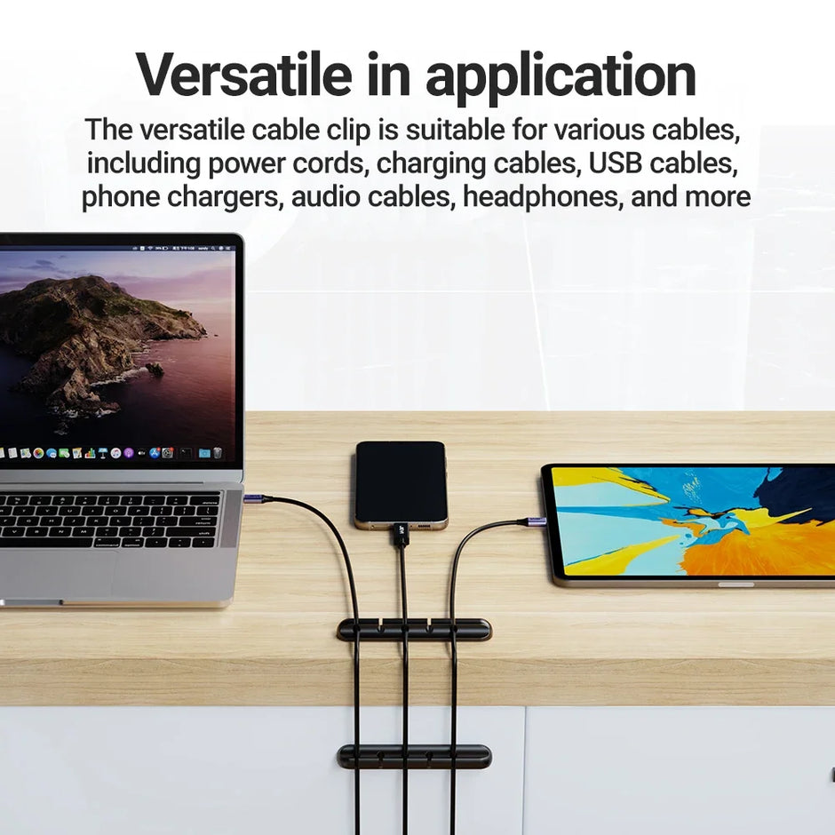Laptop and tablet with cables managed by a cable clip on a wooden surface.