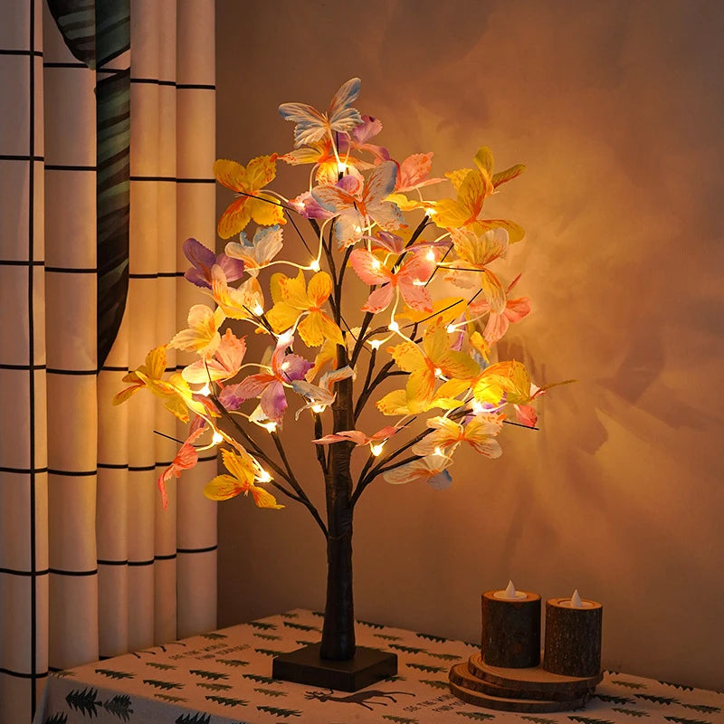 Decorative LED tree with colorful flowers on a table next to candles.