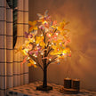 Decorative LED tree with colorful flowers on a table next to candles.