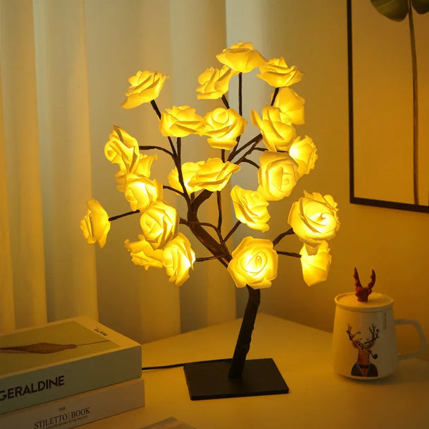 Decorative lamp shaped like a tree with illuminated yellow flowers on a table.