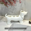 White dog-shaped ceramic brush holder on a light gray surface with a blurred background