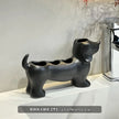 Black dog-shaped toothbrush holder on a white surface with a neutral background