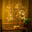 Decorative LED tree on a wooden shelf with warm lighting