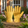 Pair of yellow gardening gloves on a garden path with flowers in the background