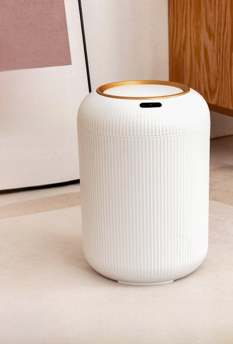 White cylindrical air purifier with gold accent on a light wooden floor.