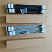 Two metal brackets with white components on a cardboard surface