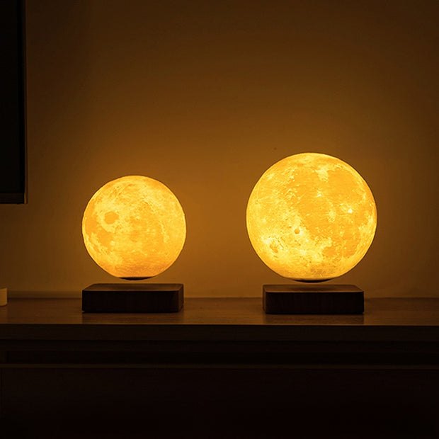 Two moon-shaped lamps on a dark surface with a warm glow.