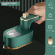 Green handheld device with gold accents being held by a hand on a black background