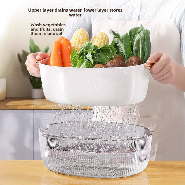 Two-tiered salad spinner with vegetables being washed on a kitchen counter.