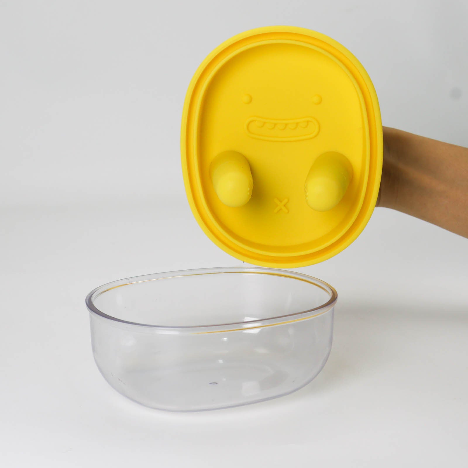 Clear glass bowl with a yellow lid on a white background